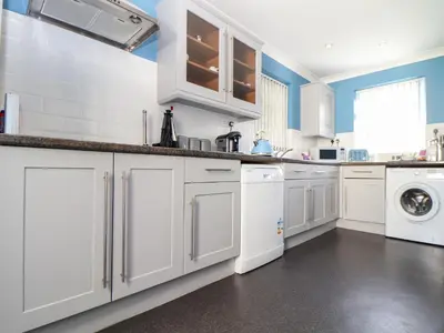 a kitchen with white cabinets and a washer and dryer at Flat 1 Niles Place in Padstow