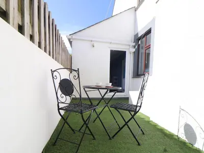 a patio with two chairs and a table on the grass at Flat 1 Niles Place in Padstow