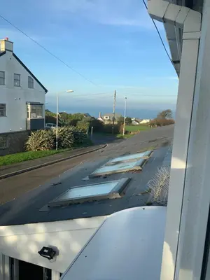 an empty road with a house and the ocean at Green Apple Bed and Breakfast in St Ives