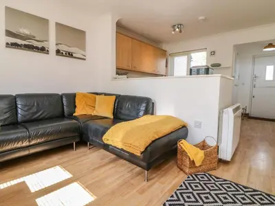 a living room with a black leather couch at Carrick Cottage in Falmouth