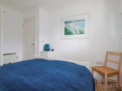a bedroom with a blue bed and a chair at Carrick Cottage in Falmouth