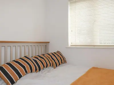 a bed with two pillows on it with a window at Carrick Cottage in Falmouth