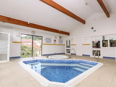 a large swimming pool in a large room with a large window at Carrick Cottage in Falmouth