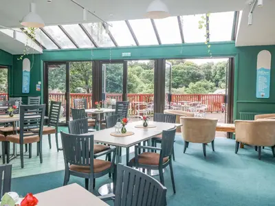 a dining room with tables and chairs and windows at Carrick Cottage in Falmouth