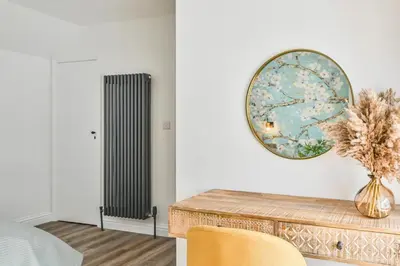 a room with a radiator and a vase of flowers at 1 Bake Cottage Serenity - Premium Coastal Retreat in Looe, Cornwall in Looe