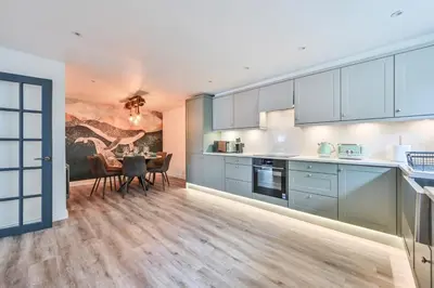 a kitchen with blue cabinets and a dining room at 1 Bake Cottage Serenity - Premium Coastal Retreat in Looe, Cornwall in Looe