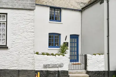 a white house with blue windows and a blue door at 1 Bake Cottage Serenity - Premium Coastal Retreat in Looe, Cornwall in Looe
