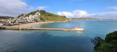 a boat in the water next to a beach at 1 Bake Cottage Serenity - Premium Coastal Retreat in Looe, Cornwall in Looe