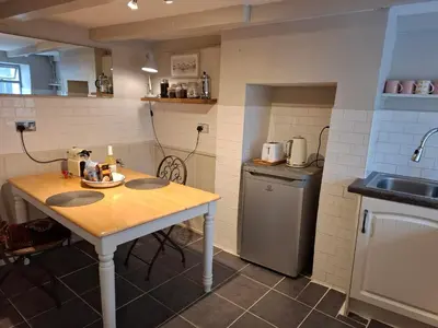 a small kitchen with a table and a sink at The Samphire Cottage in Porthleven