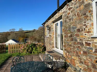 a brick building with a table and chairs on a patio at Morvoren Cottage in Launceston