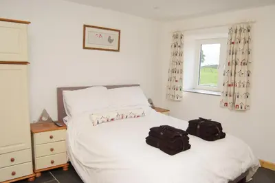 a bedroom with a bed with two bags on it at Morvoren Cottage in Launceston