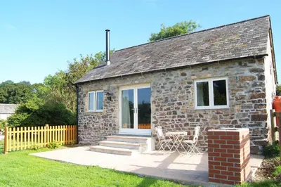 a stone cottage with a table and chairs outside at Morvoren Cottage in Launceston