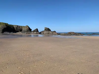 a sandy beach with rocks in the ocean at 2 Boathouse Terrace in Wadebridge