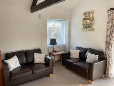 a living room with two leather couches and a table at Dozmary Cottage in Launceston