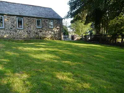 an old stone house with a large grass yard at Dozmary Cottage in Launceston