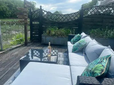 a couch sitting on a deck with a bottle of wine at 2 Bedrooms overlooking Little Petherick Creek in Little Petherick