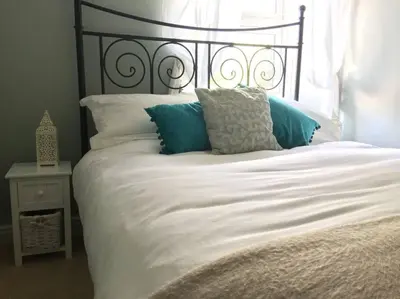 a bed with white sheets and blue pillows at Truck House, Luxury accommodation, pet friendly, Probus in Truro