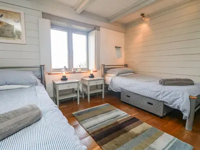 two beds in a room with two windows at An Skyber in Penzance