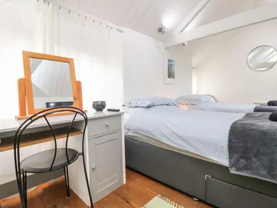 a bedroom with a bed with a mirror and a chair at An Skyber in Penzance