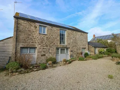 an old stone house with solar panels on the roof at An Skyber in Penzance