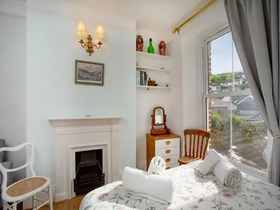 a bedroom with a bed and a fireplace and a window at Chapel House in Polruan