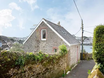 a stone house with a window and a stone wall at Chapel House in Polruan