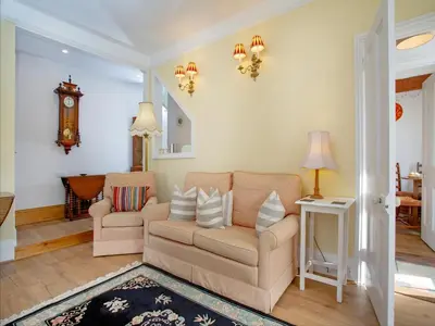 a living room with a couch and a clock on the wall at Chapel House in Polruan