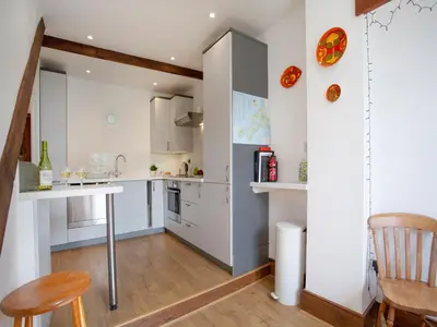 a kitchen with white cabinets and a table and chairs at Chapel House in Polruan