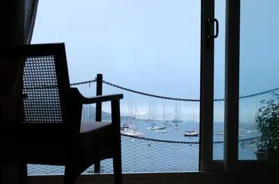 a room with a chair and a window with boats in the water at Spectacular Waterfront Views With Parking At 'Mariners Mirror' in Falmouth