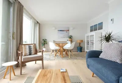 a living room with a blue couch and a table at Spectacular Waterfront Views With Parking At 'Mariners Mirror' in Falmouth