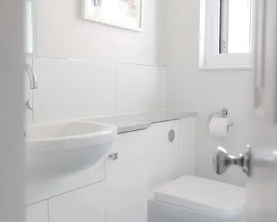 a white bathroom with a sink and a toilet at Spectacular Waterfront Views With Parking At 'Mariners Mirror' in Falmouth