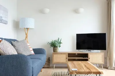 a living room with a blue couch and a tv at Spectacular Waterfront Views With Parking At 'Mariners Mirror' in Falmouth