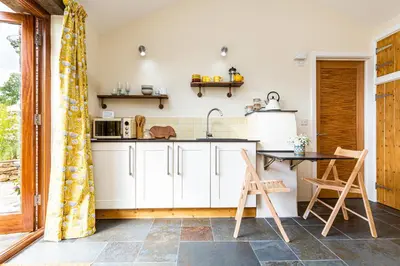 a kitchen with white cabinets and a table and chairs at Cornwall cottage The Old Piggery in Liskeard