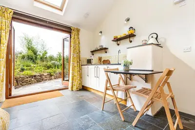 a kitchen with a table and chairs and a large window at Cornwall cottage The Old Piggery in Liskeard