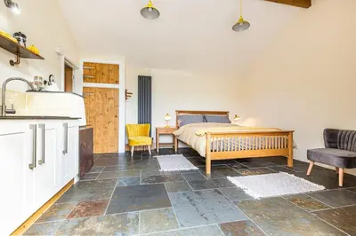 a kitchen and a bedroom with a bed and a table at Cornwall cottage The Old Piggery in Liskeard