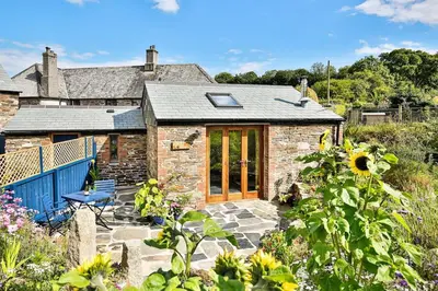a stone cottage with a patio and a sunflower at Cornwall cottage The Old Piggery in Liskeard