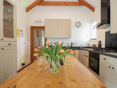 a kitchen with a vase of flowers on a wooden table at Long Barn in Penzance