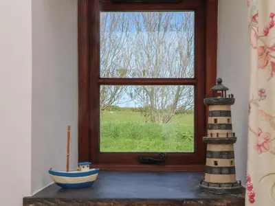 a window with a toy boat and a lighthouse at Long Barn in Penzance