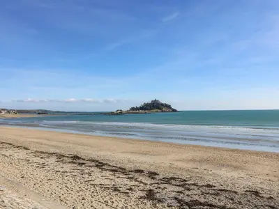 an empty beach with an island in the ocean at Long Barn in Penzance
