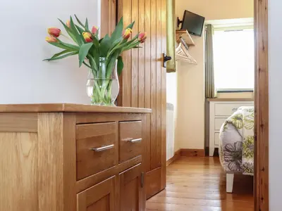 a vase of flowers on a wooden cabinet in a room at The Piggery in Penzance