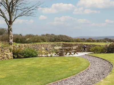a park with a picnic table and a stone wall at The Piggery in Penzance