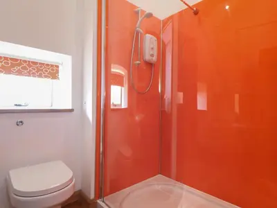 a bathroom with an orange shower with a toilet at The Piggery in Penzance