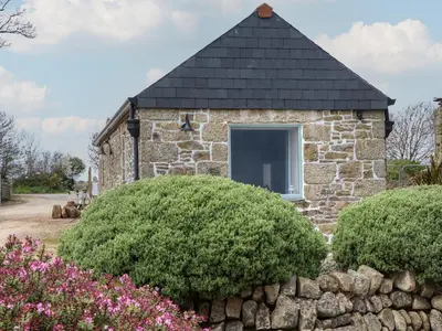 a stone house with a window and bushes at The Piggery in Penzance