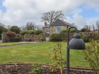 a garden with a stone house in the background at The Piggery in Penzance