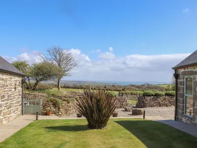 a house with a stone wall and a yard at The Piggery in Penzance