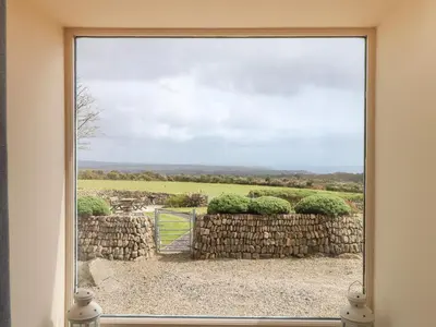 a window with a view of a stone wall at The Piggery in Penzance