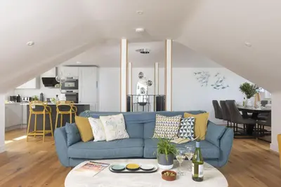 a living room with a blue couch and a kitchen at Sea views - 500 metres from the sea - Parking in St Ives