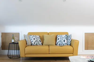 a yellow couch with pillows in a living room at Sea views - 500 metres from the sea - Parking in St Ives