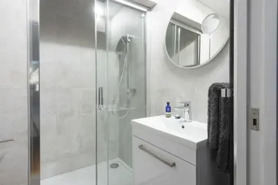 a bathroom with a shower and a sink and a mirror at Sea views - 500 metres from the sea - Parking in St Ives