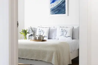 a white bedroom with a bed with white sheets and pillows at Sea views - 500 metres from the sea - Parking in St Ives
